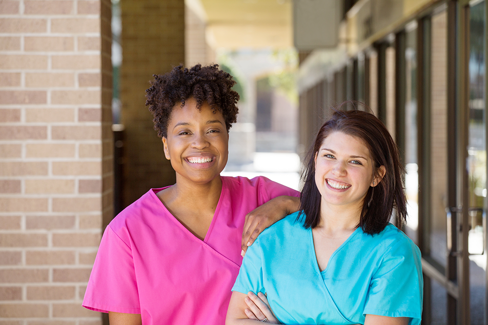 two young female coworkers posing and smiling for the camera